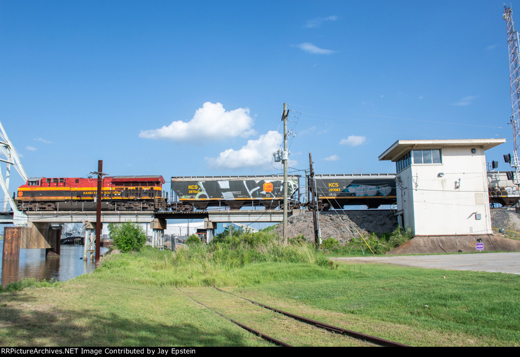 A westbound grain train passes the bridge control tower